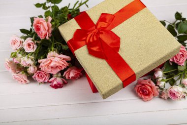 Ahşap arka planda kırmızı bir kutuda pembe güller. Çiçekli tebrik kartı.