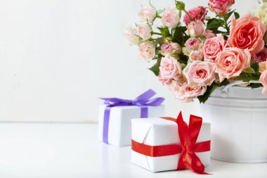 Açık ahşap arka planda hediyeli pembe güller ve kutular..