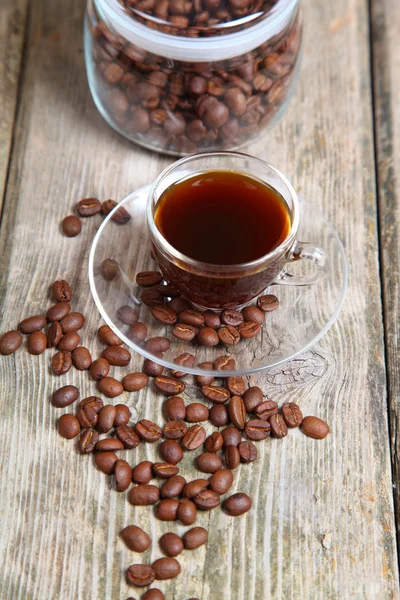 Transparante kopje koffie en koffiebonen met de bank — Stockfoto