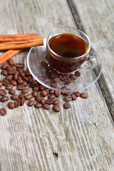 Transparent cup of coffee, beans and cinnamon sticks — Stock Photo, Image