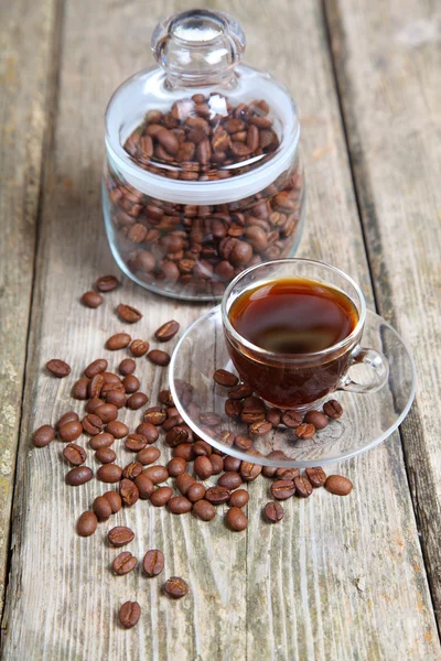 Transparente Tasse Kaffee und Kaffeebohnen mit der Bank — Stockfoto