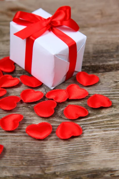 Holidays gift and red hearts on wooden background. — Stock Photo, Image