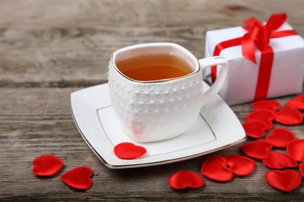 Xícara de chá, presente e corações vermelhos — Fotografia de Stock