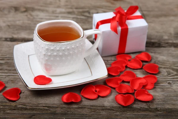 Taza de té, regalo y corazones rojos — Foto de Stock