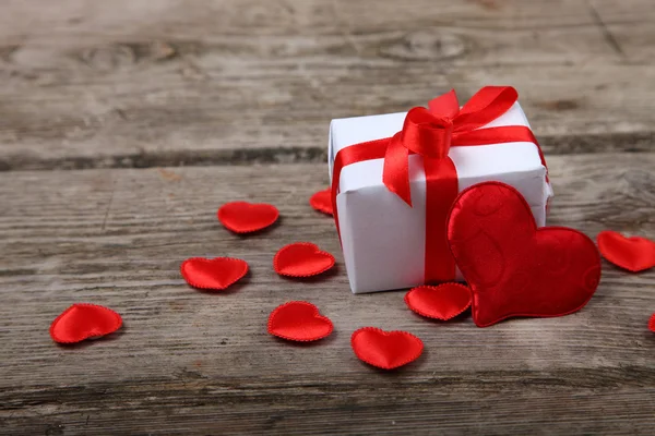 Holidays gift and red hearts on wooden background. — Stock Photo, Image