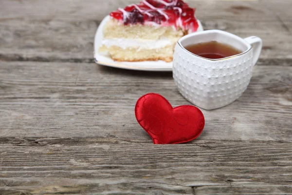 Xícara de chá, pedaço de bolo e coração vermelho — Fotografia de Stock