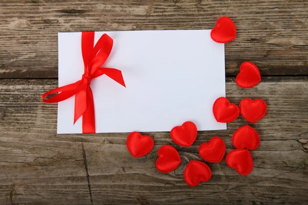 Tarjeta de felicitación con lazo rojo y corazones —  Fotos de Stock