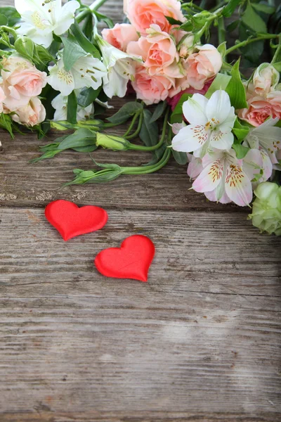 Bukett med vackra blommor och röda hjärtan — Stockfoto