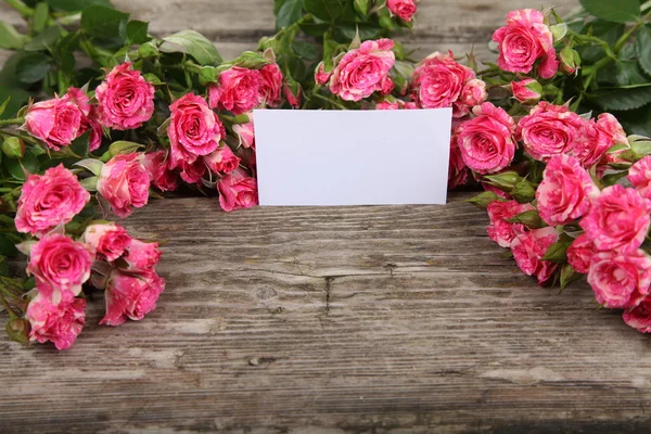 Rosa rosas e cartão de saudação — Fotografia de Stock