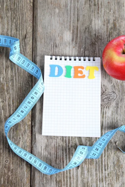 Measuring tape, notebook and apple — Stock Photo, Image