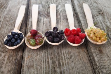 Bir tahta kaşıklar içinde farklı olgun çilek 