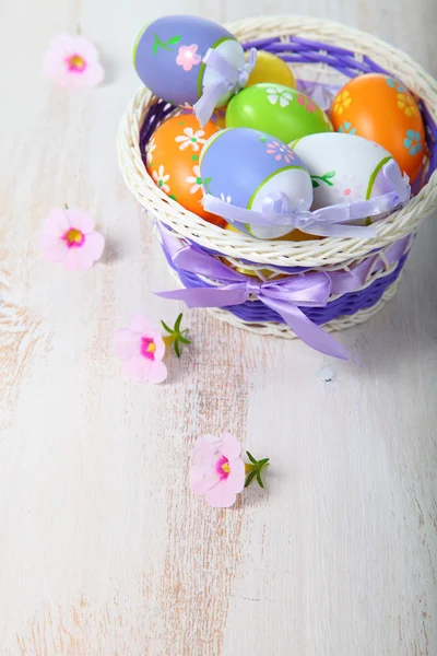 Пасхальні яйця в кошику і квіти — стокове фото