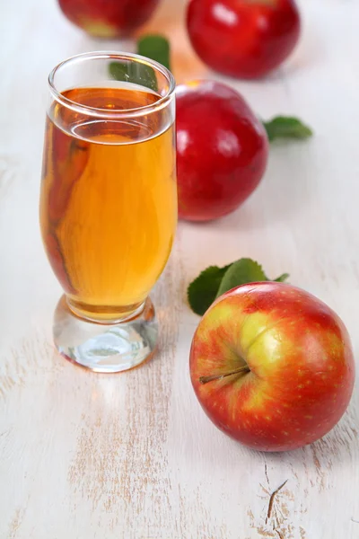 Jablečnou šťávu a jablka na dřevěný stůl — Stock fotografie
