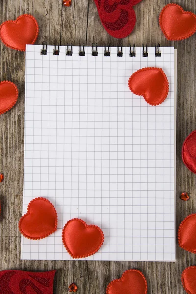 Hearts and notebook on a wooden background.