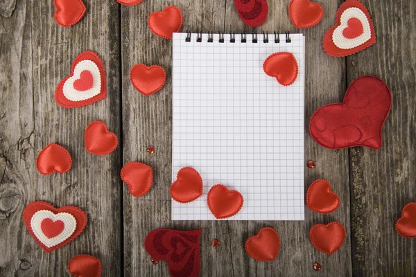 Hearts and notebook on a wooden background. — Stock Photo, Image