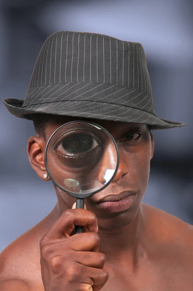 Чорний чоловік дивиться через збільшувальний стакан — стокове фото