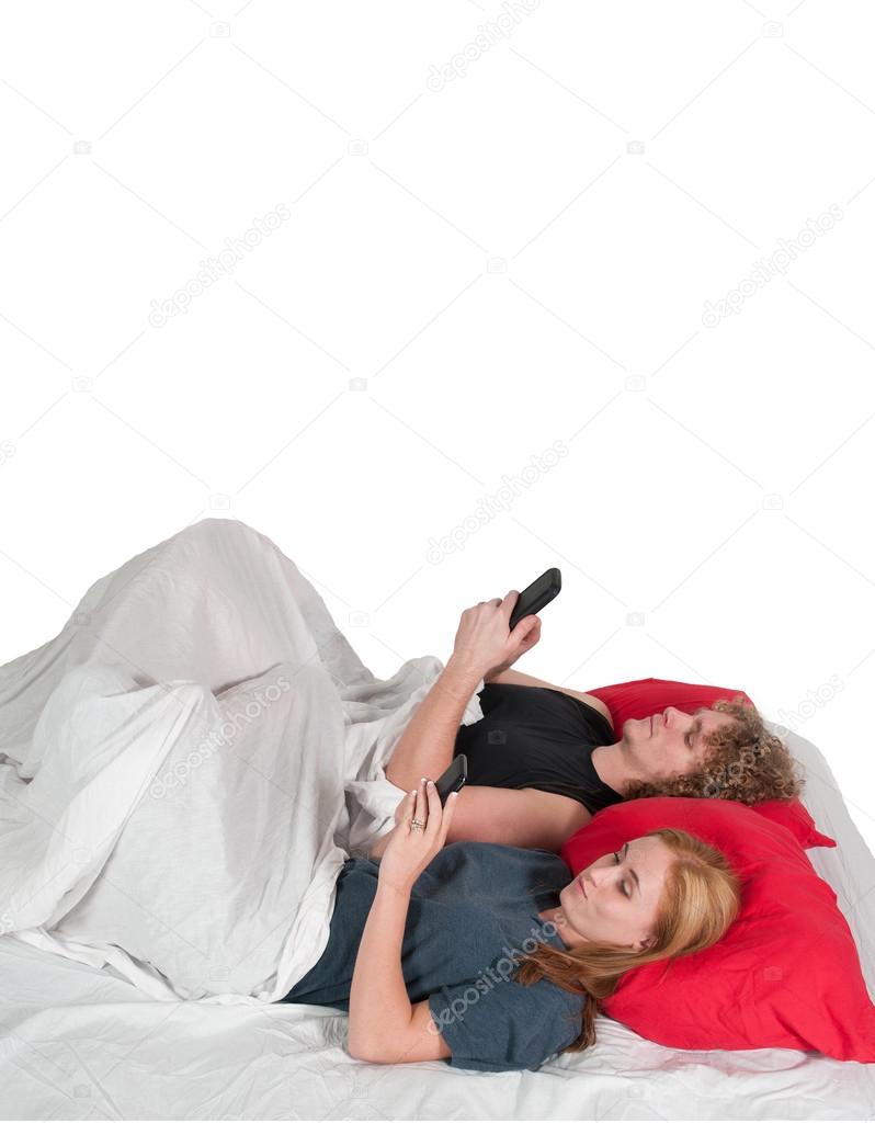 Couple texting in bed.