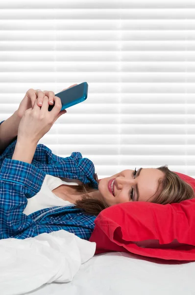 Mujer mensajes de texto en la cama — Foto de Stock