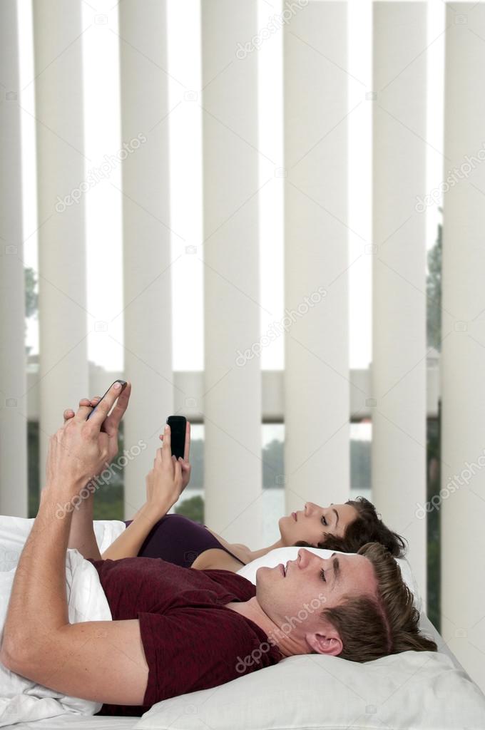 Couple texting in bed.