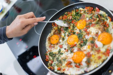 Taze yumurta ve sebzelerle kahvaltı hazırlarken.