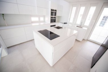 Bir dairede modern elementlerle dolu beyaz bir mutfak. 