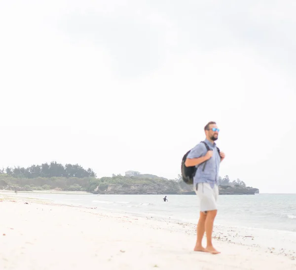 Homem adulto alegre com saco se divertindo na praia tropical — Fotografia de Stock