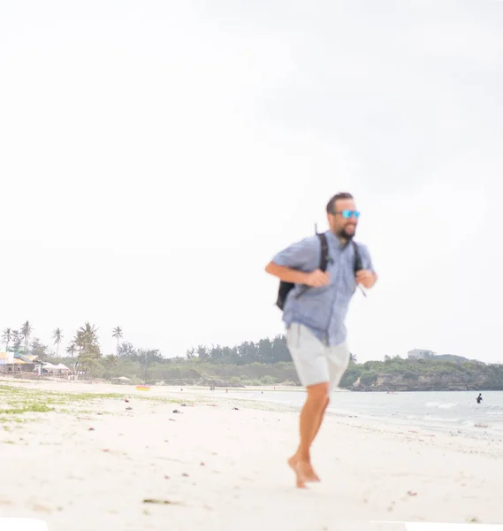 Çantalı neşeli yetişkin adam tropikal sahilde eğleniyor. Stok Fotoğraf