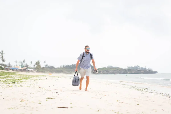 Веселий дорослий чоловік з сумкою розважається на тропічному пляжі — стокове фото