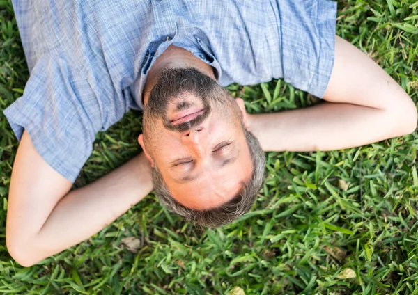 Volwassen blanke man liggend ondersteboven portret op gras weide — Stockfoto