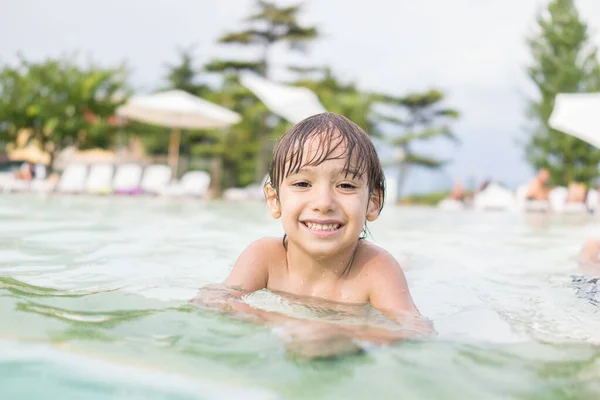 Jong jongen kind spetteren in het zwembad met plezier vrijetijdsbesteding — Stockfoto