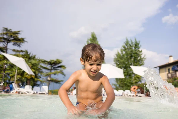 Jong jongen kind spetteren in het zwembad met plezier vrijetijdsbesteding — Stockfoto