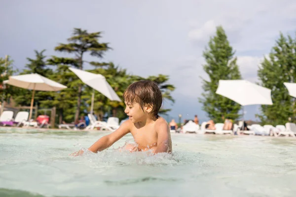 Ragazzo bambino spruzzi in piscina divertendosi attività ricreative — Foto Stock