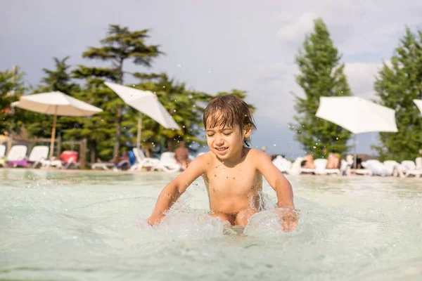 小男孩在游泳池里挥洒，进行有趣的休闲活动 — 图库照片