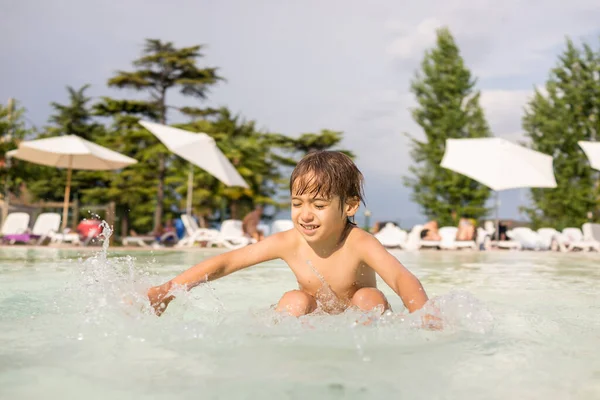 小男孩在游泳池里挥洒，进行有趣的休闲活动 — 图库照片
