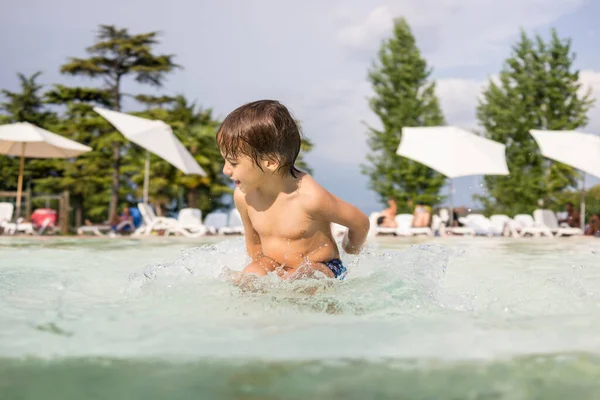 Jong jongen kind spetteren in het zwembad met plezier vrijetijdsbesteding — Stockfoto