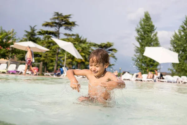 Jong jongen kind spetteren in het zwembad met plezier vrijetijdsbesteding — Stockfoto