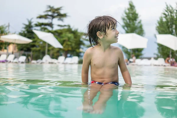 Jong jongen kind spetteren in het zwembad met plezier vrijetijdsbesteding Stockfoto