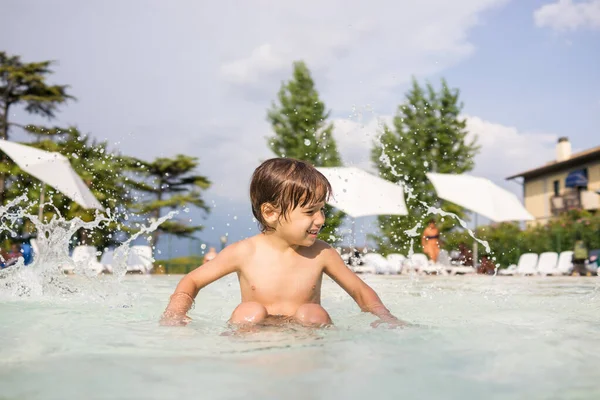 Jong jongen kind spetteren in het zwembad met plezier vrijetijdsbesteding — Stockfoto