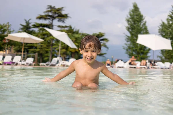 Jong jongen kind spetteren in het zwembad met plezier vrijetijdsbesteding — Stockfoto