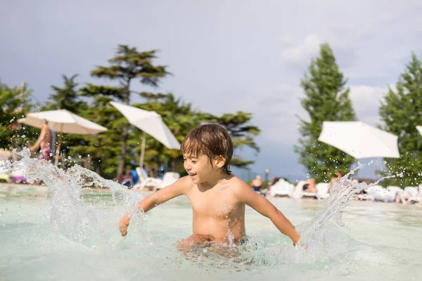 Jong jongen kind spetteren in het zwembad met plezier vrijetijdsbesteding — Stockfoto