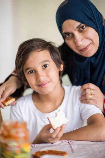 Muslimská tradiční žena se synem v kuchyni — Stock fotografie