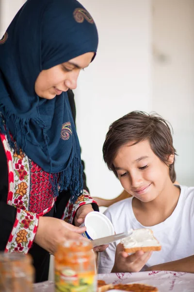 Muslimská tradiční žena se synem v kuchyni — Stock fotografie