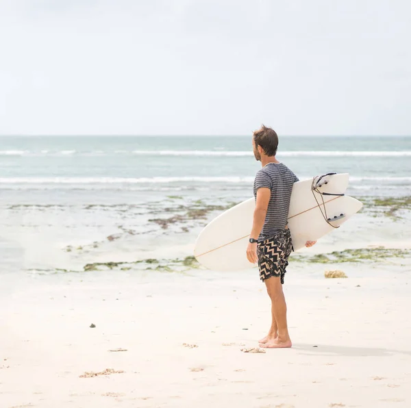 Красивый серфер с доской на берегу океана — стоковое фото