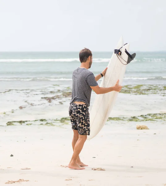 Caucásico surfista masculino con su tabla en la playa del océano Fotos De Stock