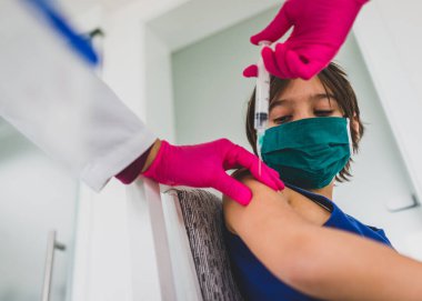 Maskeli küçük şirin çocuk iğne oluyor.