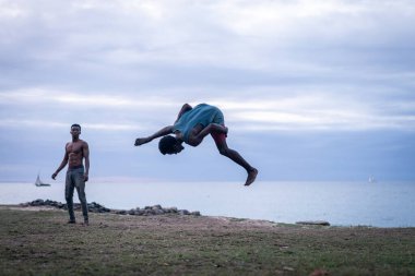 Kumsalda dövüş sanatları yapan genç adamlar.