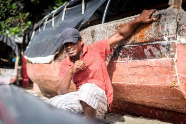 Sahilde tekneyi tamir eden Afrikalı balıkçı.