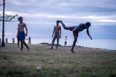 Kumsalda dövüş sanatları yapan genç adamlar.