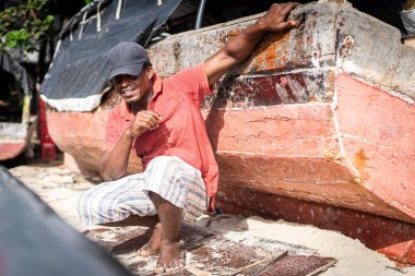 Sahilde tekneyi tamir eden Afrikalı balıkçı.