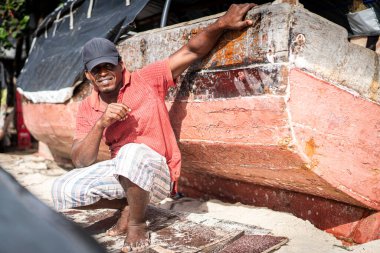 Sahilde tekneyi tamir eden Afrikalı balıkçı.